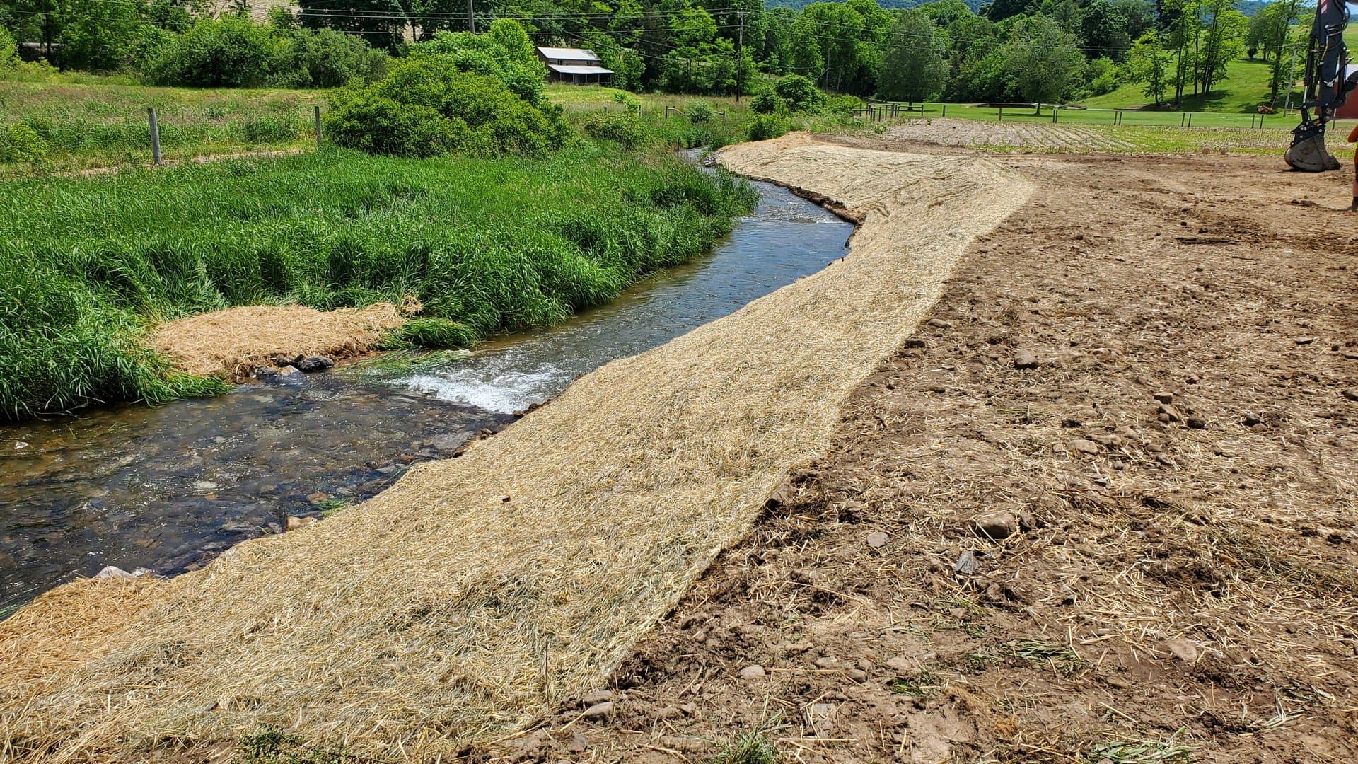 Wide view of the completed stream restoration with farmhouse on the hill